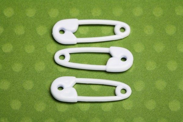 Three safety pins. Photographe : Kristin Lee