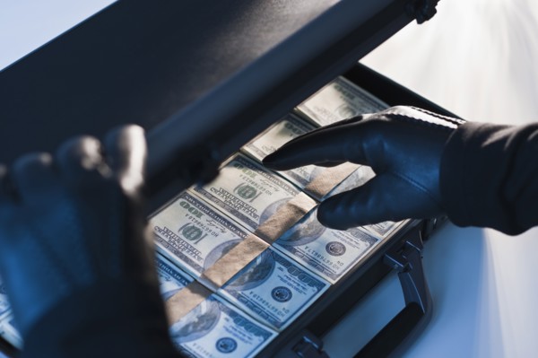 Money in a briefcase with gloved hands.