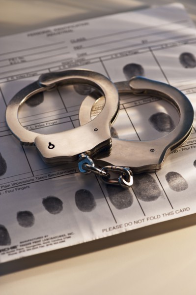 Hand cuffs on a page of fingerprints