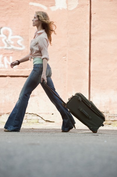 A woman walking with a suitcase.