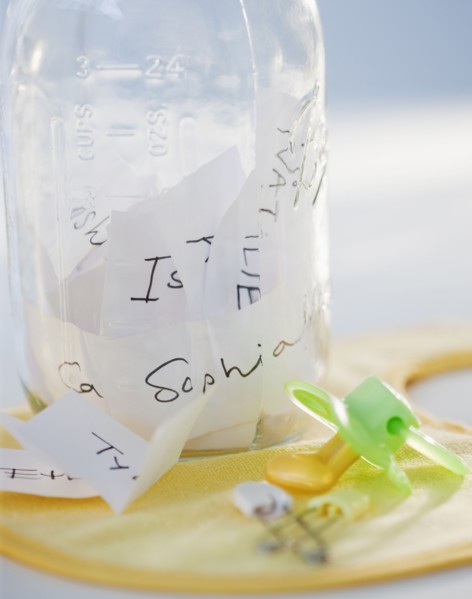 A baby bottle full of baby names beside a pacifier
