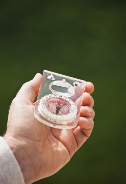 A hand holding a compass.