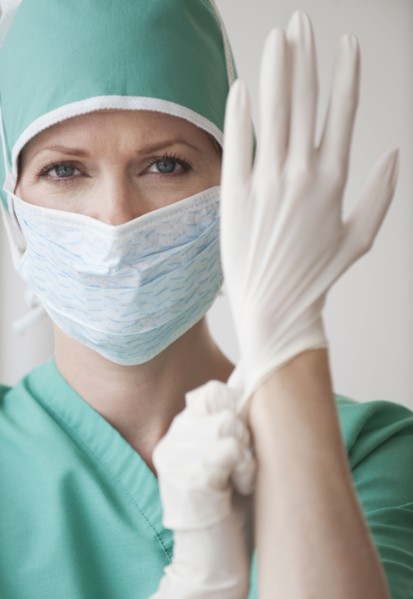 Female doctor putting on gloves.