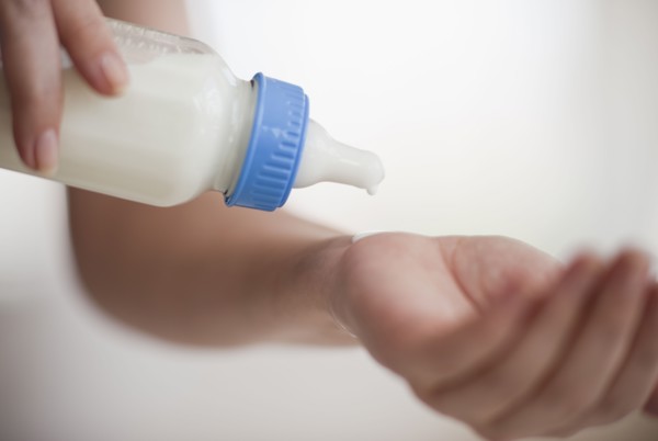 Hands holding baby bottle.