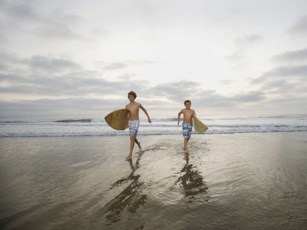 Boys running with surfboards