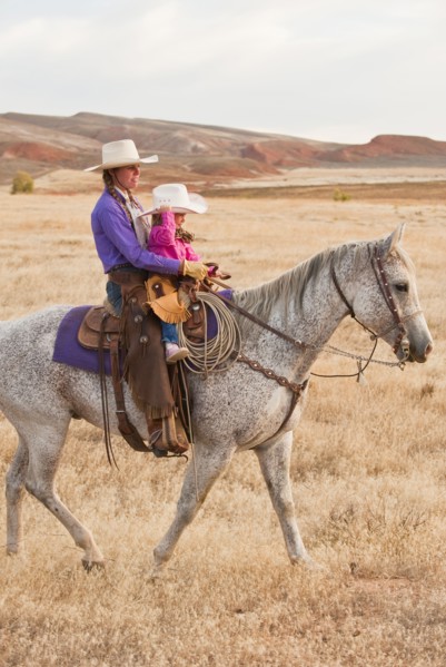 Mother and daughter riding horse.