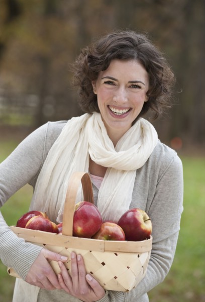 Woman holding basket of apples.