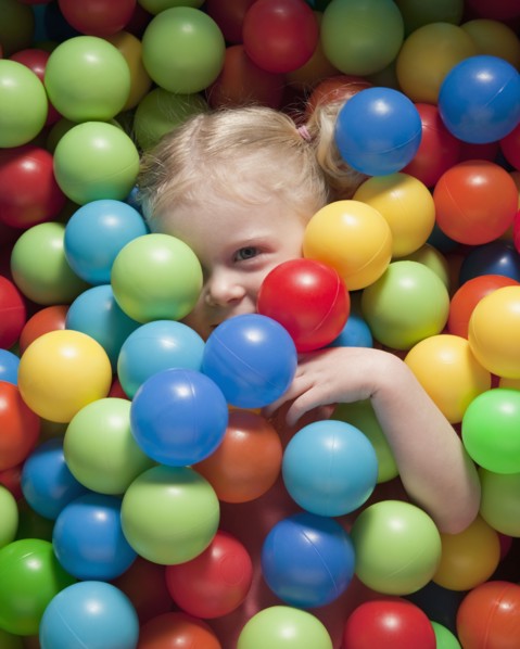 Girl hiding under balls. Photographer: Mike Kemp