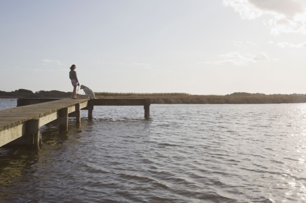 Woman and dog on pier. Photographer: Chris Hackett