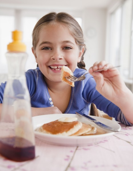 Young girl eating pancakes. Photographer: Jamie Grill