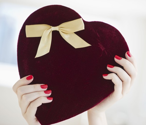 Hands holding a heart shaped box.