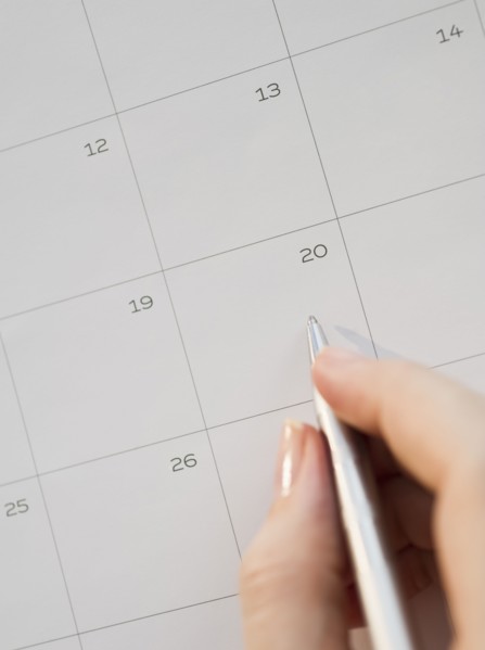 Writing with pen on calendar.