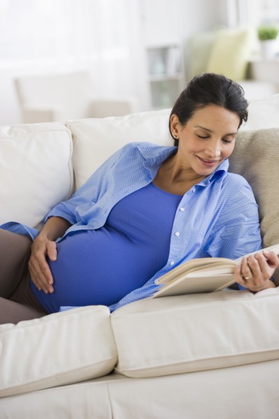 Pregnant woman reading on couch.