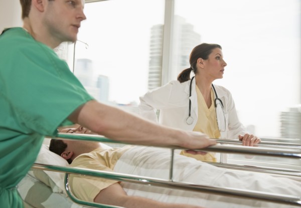 Healthcare workers pushing gurney in emergency room.