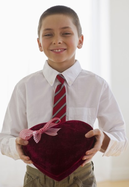 Young boy holding a box of chocolates.