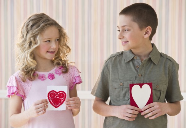 Young children holding Valentine cards.