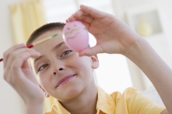 Young boy decorating an Easter egg.