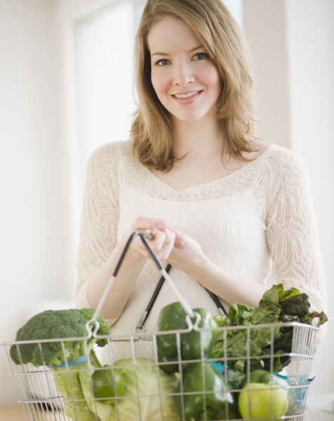 Woman holding basket of green vegetables. Photographe : Jamie Grill