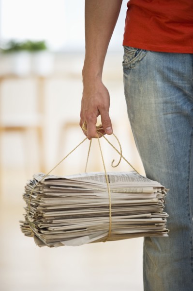 Man holding stack of newspapers. Photographe : Daniel Grill