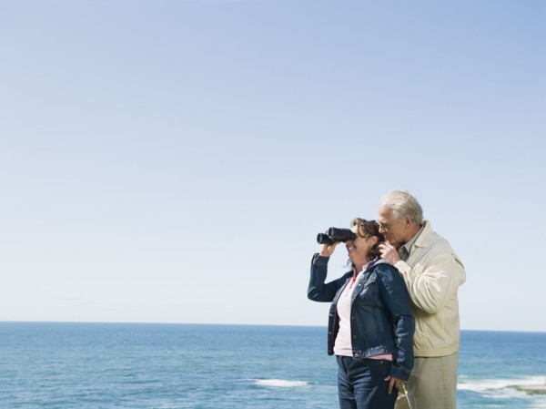 Couple looking at ocean with binoculars.