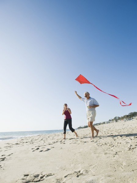 Couple flying kite on beach.