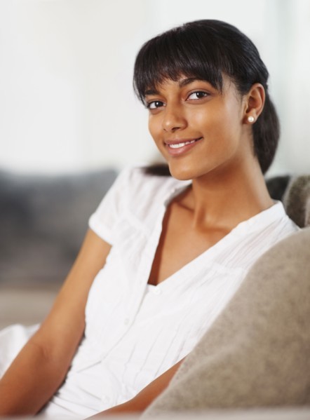 Young woman sitting on couch. Photographe : momentimages