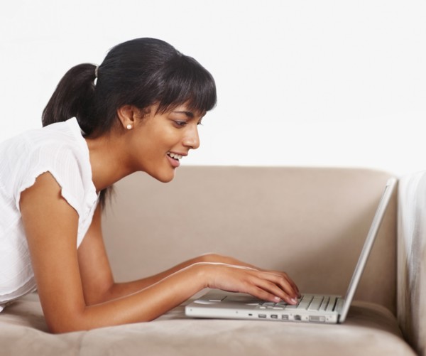 Young woman typing on laptop. Photographe : momentimages