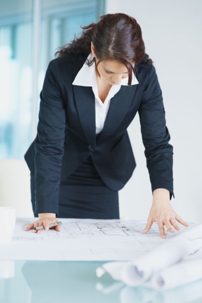 Businesswoman looking at blueprints. Photographe : momentimages