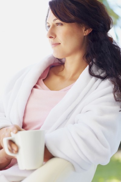 Woman in bathrobe drinking coffee. Photographe : momentimages