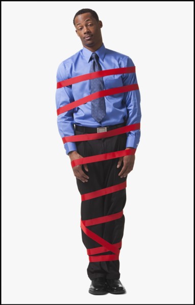 Businessman wrapped in red tape. Photographe : Mike Kemp