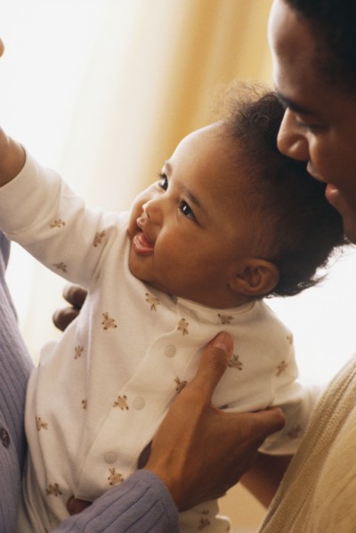 Close-up of mother and father holding their baby. Photographe : Rob Lewine