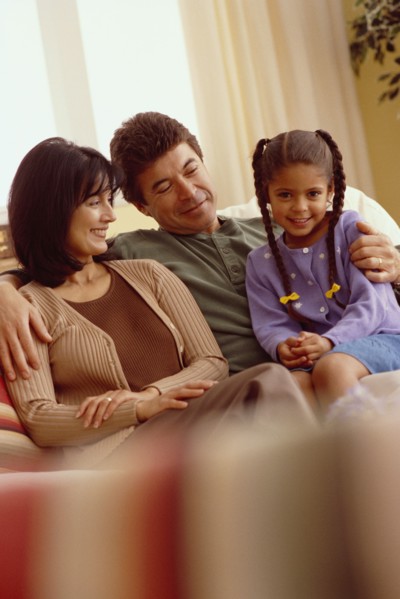 Young girl and her parents relaxing on the couch. Photographe : Rob Lewine