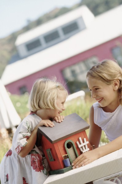 Siblings playing outdoors with a toy house. Photographe : Rob Lewine