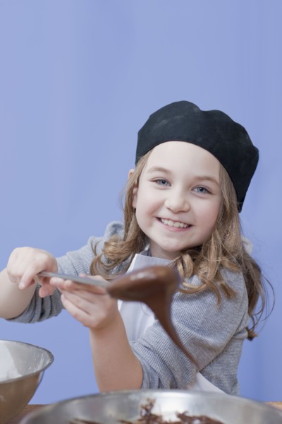 Young girl holding a mixing spoon. Photographe : Dan Bannister