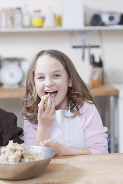 Young girl eating cookie batter. Photographe : Dan Bannister