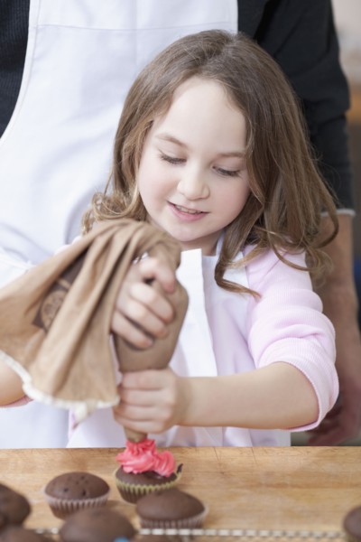 Young girl decorating cupcakes. Photographe : Dan Bannister