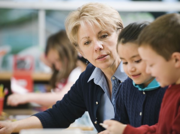 Teacher sitting at table with kindergarten students.
