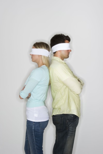 Blindfolded couple standing back to back.