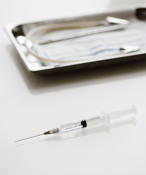 Syringe beside tray of medical supplies. Photo : Jamie Grill