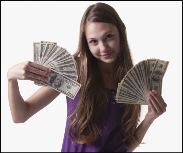 Teenage girl holding several 100 dollar bills. Photo : Mike Kemp