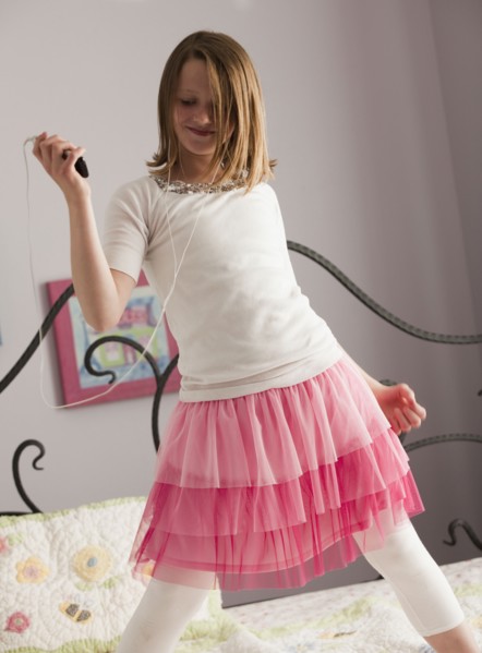 Young girl dancing on her bed. Photo : Mike Kemp