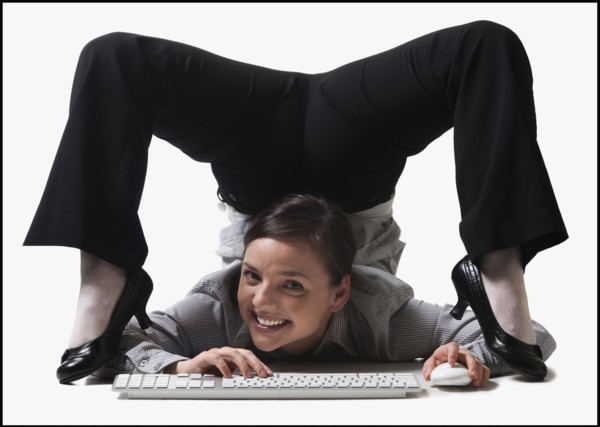 Businesswoman contorting her body while typing. Photo : Mike Kemp