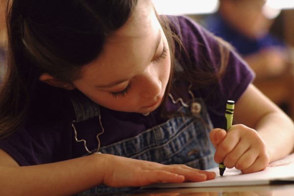 Elementary school student coloring with green crayon. Photo : Rob Lewine