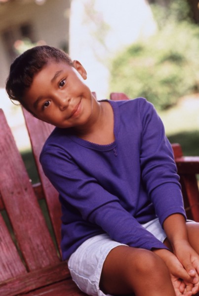 Cute young girl sitting outdoors on chair in summer. Photo : Rob Lewine
