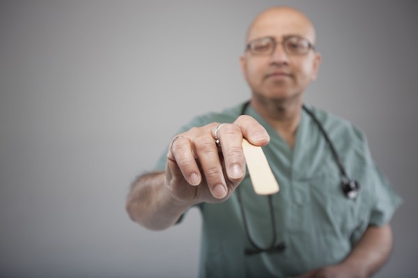Doctor holding a tongue depressor. Photo : Dan Bannister