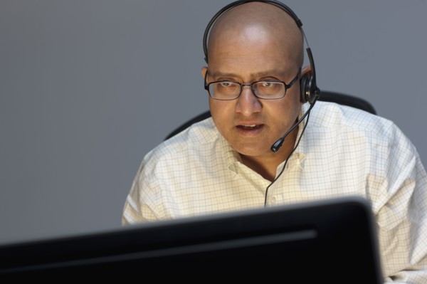 Man wearing headset working on computer. Photo : Dan Bannister