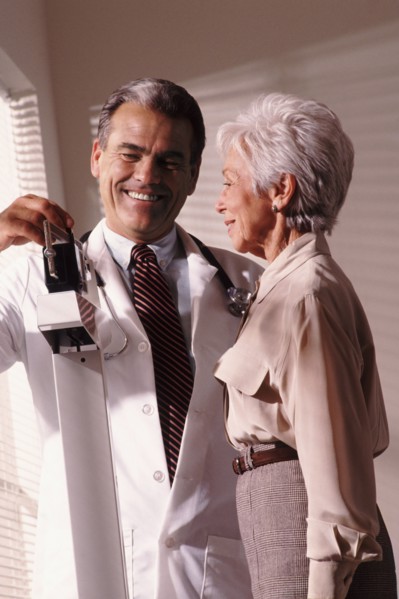 Doctor weighing senior patient. Photo : Rob Lewine