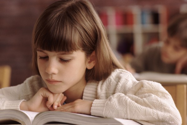 Elementary school student reading book at her desk. Photo : Rob Lewine