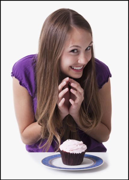 Excited teenage girl about to eat a cupcake. Photo : Mike Kemp