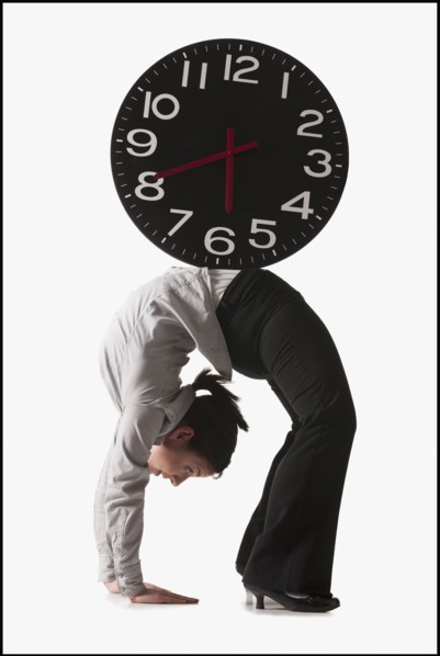 Clock on top of businesswoman bending over backwards. Photo : Mike Kemp